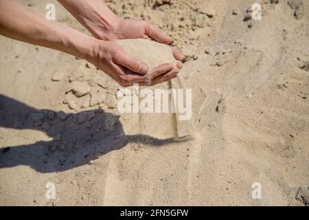 Homme tenant le sable dans ses mains Banque D'Images