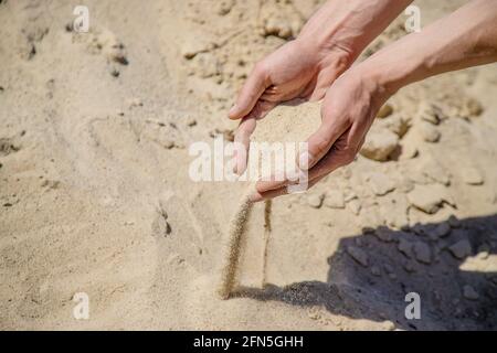 Homme tenant le sable dans ses mains Banque D'Images