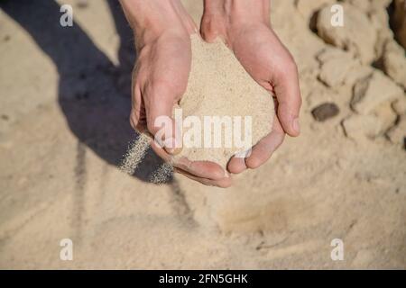 Homme tenant le sable dans ses mains Banque D'Images