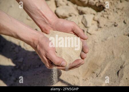 Homme tenant le sable dans ses mains Banque D'Images