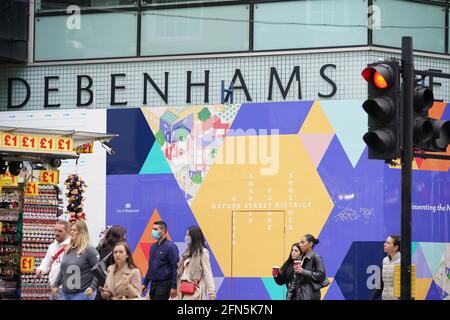 Les gens marchent à pied devant l'ancien magasin de drapeaux Debenhams à Oxford Street, Londres. Debenhams va fermer ses portes pour la dernière fois de son histoire de 243 ans. La chaîne historique des grands magasins fermera ses 28 magasins restants à travers le Royaume-Uni pour de bon samedi après l'effondrement de l'entreprise dans le contexte de la pandémie du coronavirus. Date de la photo: Vendredi 14 mai 2021. Banque D'Images
