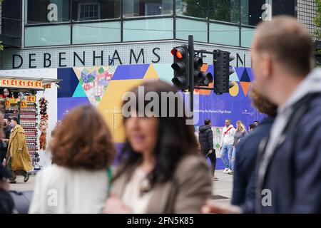 Les gens marchent à pied devant l'ancien magasin de drapeaux Debenhams à Oxford Street, Londres. Debenhams va fermer ses portes pour la dernière fois de son histoire de 243 ans. La chaîne historique des grands magasins fermera ses 28 magasins restants à travers le Royaume-Uni pour de bon samedi après l'effondrement de l'entreprise dans le contexte de la pandémie du coronavirus. Date de la photo: Vendredi 14 mai 2021. Banque D'Images
