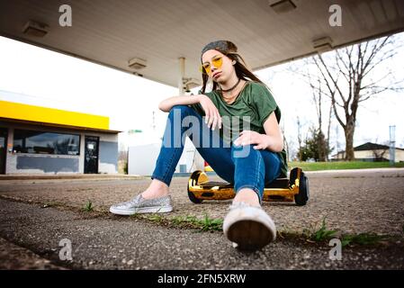 Cool Tween girl with blond hair and sungévalue assis planque Banque D'Images