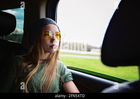 Belle fille entre les cheveux longs blonds et les lunettes de soleil en voiture. Banque D'Images