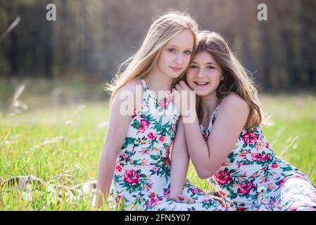 Deux jeunes filles adolescentes en sundresses assises sur une couverture à l'extérieur. Banque D'Images