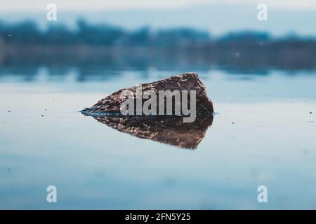 roche dépassant de la surface de l'eau calme Banque D'Images