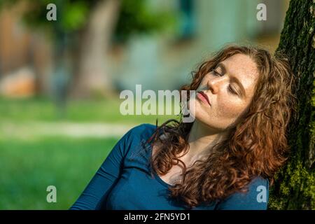 Portrait de charmante jeune femme à tête rouge avec des taches de rousseur profitant du soleil Banque D'Images