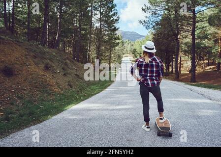 Une femme avec un skateboard sur une route de montagne Banque D'Images