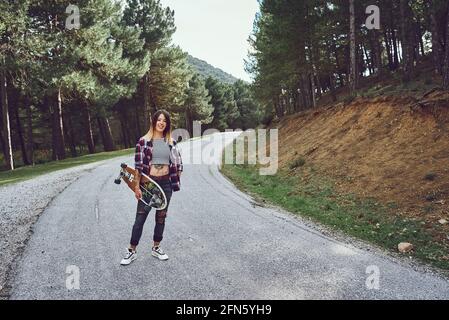 Une femme avec un skateboard sur une route de montagne Banque D'Images