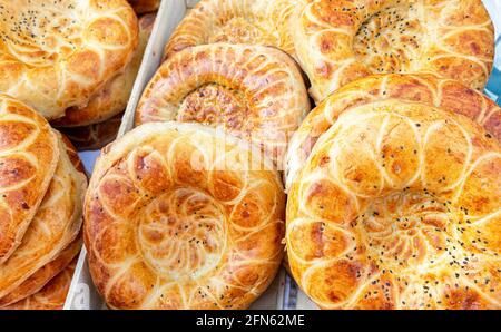 Pains plats ouzbèkes frais avec graines de sésame du tandir. Pain plat traditionnel de l'est. Concept de cuisine nationale Banque D'Images