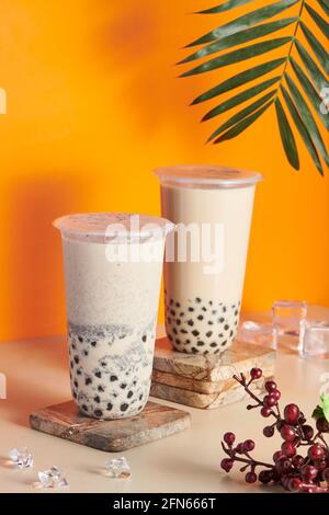 Tasses en plastique remplies de thé au lait frais et savoureux sur une montagne en bois sur la table Banque D'Images