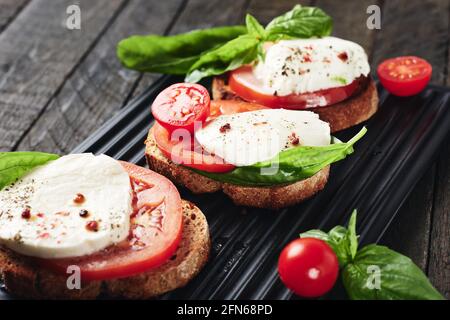 Sandwichs ouverts ou bruschetta au fromage mozzarella, tomates et basilic, caprese. Banque D'Images