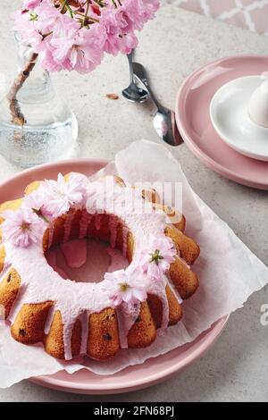 Gâteau Bundt festif aux couleurs roses, orné de fleurs de cerisier. Banque D'Images