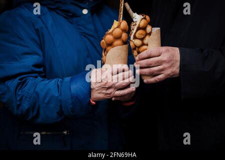 Gaufres aux œufs de style Hong Kong entre les mains. Délicieux gaufre à bulles avec crème glacée, biscuits et sirop de caramel dans les mains de couples seniors. Cuisine tendance Banque D'Images