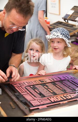 Les sœurs regardent l'impression faite à la main sur une presse d'une affiche pour célébrer l'art en action Festival Waterperry House, Oxfordshire, Royaume-Uni, en juillet 2016. (123) Banque D'Images