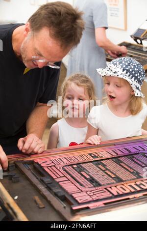 Les sœurs regardent l'impression faite à la main sur une presse d'une affiche pour célébrer l'art en action Festival Waterperry House, Oxfordshire, Royaume-Uni, en juillet 2016. (123) Banque D'Images