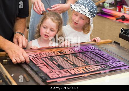 Les sœurs regardent l'impression faite à la main sur une presse d'une affiche pour célébrer l'art en action Festival Waterperry House, Oxfordshire, Royaume-Uni, en juillet 2016. (123) Banque D'Images