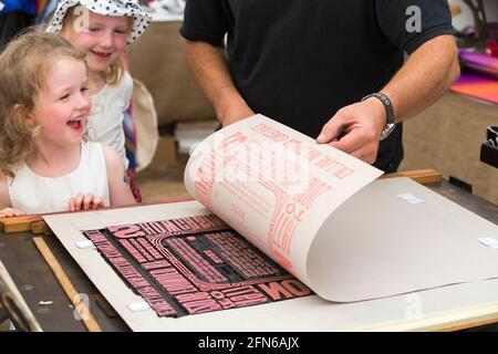 Les sœurs regardent l'impression faite à la main sur une presse d'une affiche pour célébrer l'art en action Festival Waterperry House, Oxfordshire, Royaume-Uni, en juillet 2016. (123) Banque D'Images