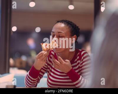 Une jeune femme mange une pizza du service de livraison au bureau Banque D'Images