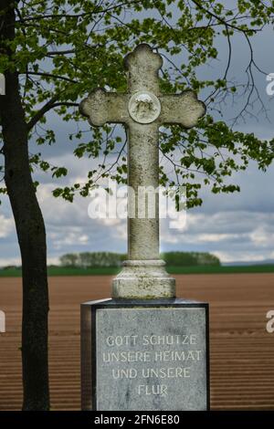 Calvaire avec l'inscription 'Dieu bénisse notre maison et nos champs' en arrière-plan asperges champs à Zuelpich. Banque D'Images