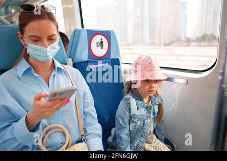 Dubaï, Émirats arabes Unis - MARS 2020 : une femme sous masque et sa petite fille assise en voiture du métro de Dubaï Banque D'Images