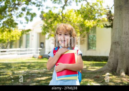 Retour à l'école. Enfant avec sacs à dos debout dans le parc près de l'école. Élèves avec des livres et des sacs à dos à l'extérieur. Banque D'Images