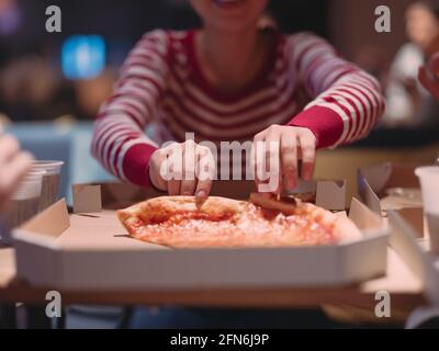 Une jeune femme mange une pizza du service de livraison au bureau Banque D'Images