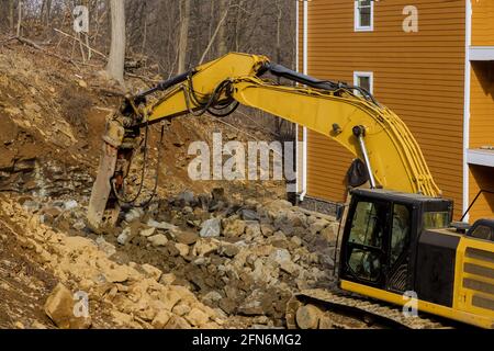 Tracteur pour l'écrasement de grosses pierres sur un pendant les travaux de terrassement au chantier de construction en montagne Banque D'Images