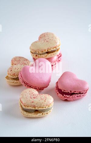 Un groupe de biscuits de macaron français en forme de coeur, saveur de vanille et de fraise, espace de copie sur fond neutre, vertical Banque D'Images