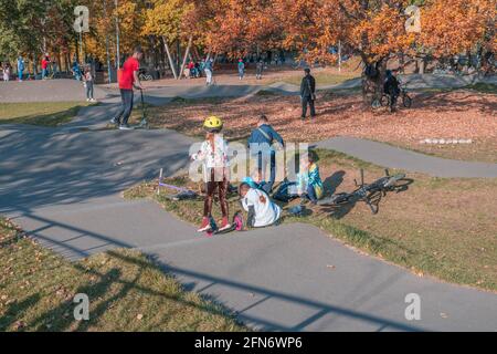 Kazan, Russie - 03 octobre 2020 : les enfants et les adolescents passent des scooters et des vélos dans le parc public de la ville d'automne Banque D'Images