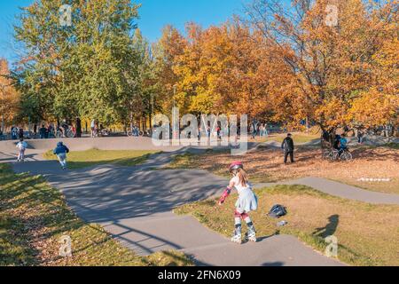 Kazan, Russie - 03 octobre 2020 : les enfants et les adolescents font du vélo, des scooters et des patins à roulettes dans le parc public de la ville, par une journée ensoleillée en automne Banque D'Images