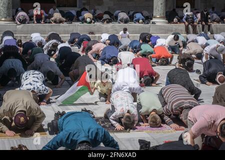 Istanbul, Turquie. 14 mai 2021. Un garçon porte un drapeau palestinien pendant une séance de prière.les gens prient pour les Palestiniens qui sont morts après les attaques d'Israël sur la bande de Gaza. Des gens se sont rassemblés devant la mosquée Fatih à Istanbul pour protester contre les attentats. Crédit : SOPA Images Limited/Alamy Live News Banque D'Images