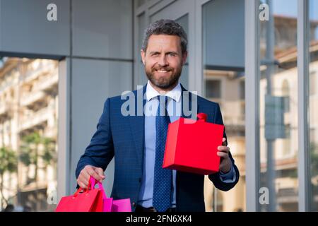 Grand cadeau. Homme avec boîte cadeau et souriant tout en se tenant contre la ville. Banque D'Images