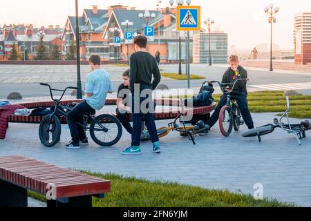 Kazan, Russie - 03 octobre 2020 : un groupe d'adolescents se détendent dans un parc de la ville à côté de leurs vélos au coucher du soleil Banque D'Images