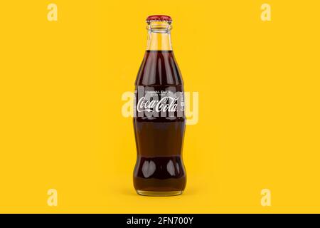Une bouteille de Coca-Cola de forme traditionnelle sur fond jaune. Banque D'Images