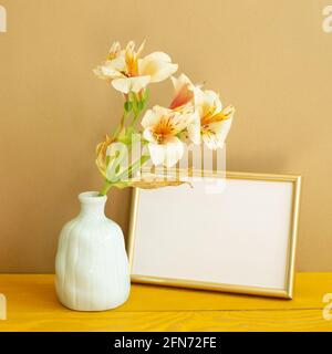 Cadre photo vide avec fleurs sur table en bois. Fond marron Banque D'Images
