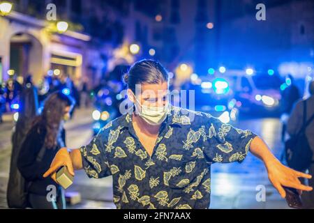 Barcelone, Espagne. 14 mai 2021. L'homme est vu danser devant les voitures de police dans les rues de Barcelone. Le premier week-end sans état d'alarme et sans couvre-feu à Barcelone, les rues du centre-ville sont remplies de personnes se rencontrant pour boire sans distance de sécurité ou masque de protection. La police a effectué une opération d'expulsion. Crédit : SOPA Images Limited/Alamy Live News Banque D'Images