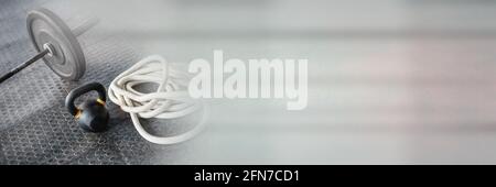 Composition de barbell, de kettlebell et de corde sur le sol de la salle de sport avec lumière grise floue Banque D'Images