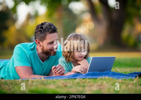 Concept d'éducation familiale. Père enseignant à son fils comment utiliser un ordinateur portable, ordinateur portable. Banque D'Images