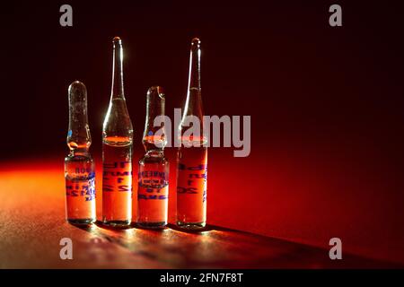 quatre flacons avec médicament injectable sur fond rouge. Banque D'Images