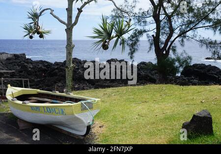 Vieux bateau de pêche en bois amarré sur la rive le long de la côte de lave de l'îlot tropical de la Réunion, France Banque D'Images