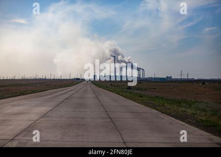 Pavlodar, Kazakhstan: Large chemin de dalles de béton. Silhouette de la centrale électrique à l'horizon. Ciel gris nuageux. Banque D'Images