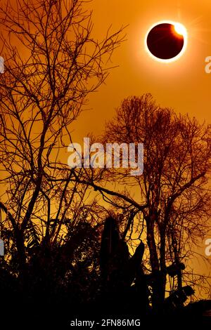 Phénomène scientifique naturel étonnant. La proéminence et la corona du soleil interne. éclipse solaire totale avec effet d'anneau de diamant brillant sur le ciel orange au-dessus Banque D'Images