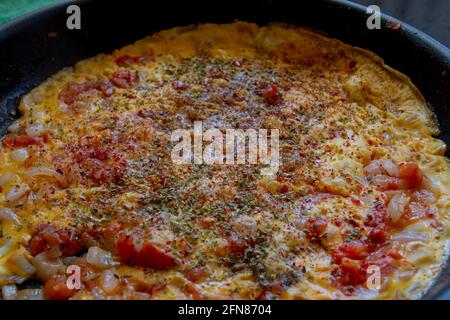 Repas traditionnel de petit déjeuner turc où les œufs brouillés, les tomates, les oignons et les poivrons sont cuits ensemble dans une casserole: menemen Banque D'Images