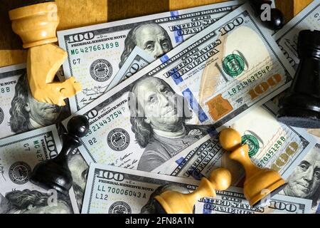 Billets de dollar et jeu d'échecs, vue du dessus de la monnaie papier américaine et des pièces d'échecs sur l'échiquier. Concept de stratégie monétaire, concurrence déloyale, pari, stoc Banque D'Images