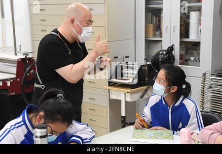 (210515) -- BEIJING, 15 mai 2021 (Xinhua) -- Wang Kun utilise le langage des signes pour communiquer avec les élèves de l'école spéciale d'éducation Jianxiang de Beijing, à Beijing, capitale de la Chine, le 13 mai 2021. Wang Kun, 47 ans, est professeur d'art pour malentendants à l'école spéciale d'éducation Jianxiang de Beijing. Travailler en tant que professeur d'éducation spéciale a été difficile. Wang Kun continue d'apprendre, de lire et de communiquer avec d'autres enseignants pour établir ses méthodes d'enseignement uniques. « en classe, j'utilise habituellement des exemples et des comparaisons vifs pour expliquer des théories compliquées de l'art. En même temps, je recommanderais des livres Banque D'Images