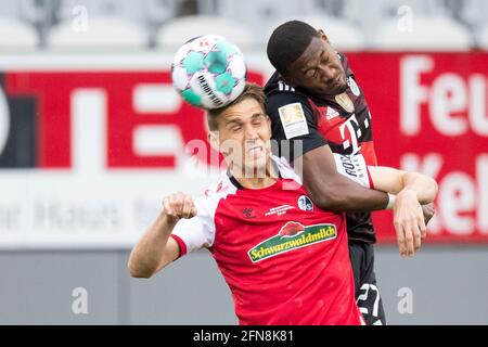 Freiburg im Breisgau, Allemagne. 15 mai 2021. Football: Bundesliga, SC Freiburg - Bayern Munich, 33ème jour de match à Schwarzwald-Stadion. Nils Petersen de Fribourg (l) en action contre David Alaba (r) de Munich. Crédit : Tom Weller/dpa - REMARQUE IMPORTANTE : Conformément aux règlements de la DFL Deutsche Fußball Liga et/ou de la DFB Deutscher Fußball-Bund, il est interdit d'utiliser ou d'avoir utilisé des photos prises dans le stade et/ou du match sous forme de séquences et/ou de séries de photos de type vidéo./dpa/Alay Live News Banque D'Images