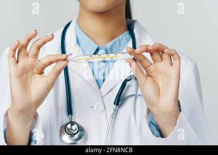 femme médecin avec un thermomètre dans ses mains et un stéthoscope autour de son cou Banque D'Images