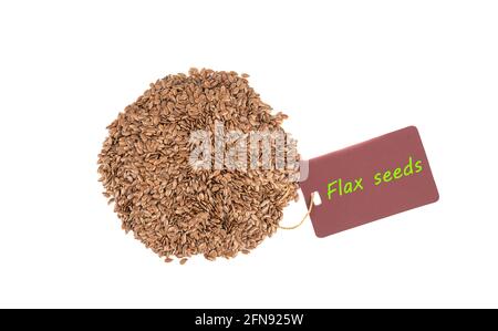 Pile de graines de lin sur fond blanc et étiquette avec inscription Flax Seeds. Pose à plat. Vue de dessus. Copier l'espace. Banque D'Images
