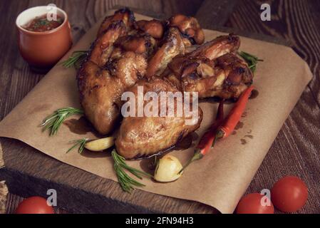 De délicieuses ailes de poulet frite se trouvent sur le plateau de service, décorées avec diverses épices, herbes et légumes. Mise au point sélective. Banque D'Images